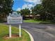 Palm Aire Country Club entrance with a classic clubhouse sign and winding driveway through lush grounds at 5630 Golf Pointe Dr # 108, Sarasota, FL 34243