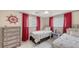 Bright bedroom showcasing twin beds, red curtains, and nautical decor at 755 Taplow Rd, Venice, FL 34293