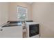 Bright laundry room with a window, modern washer and dryer, and convenient storage for laundry supplies at 867 Bacon Ave, Sarasota, FL 34232