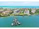 Stunning aerial view of beachfront condos, a pier, and boats on the sparkling turquoise waters of the Gulf at 8701 Midnight Pass Rd # 206A, Sarasota, FL 34242