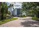 A beautiful tree lined brick driveway leading to the entrance of the condo building at 8701 Midnight Pass Rd # 206A, Sarasota, FL 34242