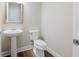 Neat half bathroom features a pedestal sink, modern toilet, and wood-look flooring at 8752 Coastal Key Way, Parrish, FL 34219