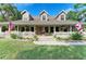 Charming home with three dormers, covered porch with white railing, American and Florida flags, and lush lawn at 906 134Th E St, Bradenton, FL 34212