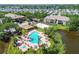 Aerial view of a community pool, spa, and sand volleyball court next to a pond, surrounded by lush greenery at 10265 Gandy N Blvd # 1004, St Petersburg, FL 33702