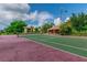 Outdoor tennis court with green and red surface surrounded by lush landscaping and neighborhood buildings at 10265 Gandy N Blvd # 1004, St Petersburg, FL 33702