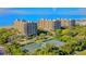 Aerial view showcasing lush landscaping, tennis courts, and beachfront condominiums at 1211 Gulf Of Mexico Dr # 704, Longboat Key, FL 34228