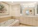 Bathroom features a soaking tub with marble surround, white cabinets, and dual sinks at 1211 Gulf Of Mexico Dr # 704, Longboat Key, FL 34228