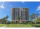 Exterior view of modern high rise condo building with manicured landscaping and palm trees at 1211 Gulf Of Mexico Dr # 704, Longboat Key, FL 34228