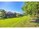 Lush backyard with manicured lawn, mature landscaping, and multiple homes featuring screened-in patios at 12710 Coastal Breeze Way, Bradenton, FL 34211