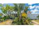 Charming home surrounded by a landscaped yard, featuring a palm tree, garden, and a screened porch at 13492 Dibella Ave, Port Charlotte, FL 33981