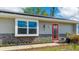 Close-up of home featuring a vibrant red front door, updated siding, and a large window providing ample natural light at 13492 Dibella Ave, Port Charlotte, FL 33981