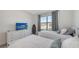 Comfortable bedroom with two twin beds, a white dresser with TV, and a view of the neighborhood through the window at 15332 Serene Shores Loop St, Bradenton, FL 34211