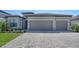 Two car garage with grey doors and stone veneer accents, set in a gray home with a paved driveway at 15332 Serene Shores Loop St, Bradenton, FL 34211
