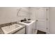Well-lit laundry room with modern washer and dryer, granite countertop sink, and convenient wire shelving for storage at 15332 Serene Shores Loop St, Bradenton, FL 34211