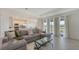 Bright living room with tile floors, comfortable gray sofa, and view of the lush backyard at 15332 Serene Shores Loop St, Bradenton, FL 34211
