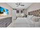 Primary bedroom featuring a luxurious upholstered headboard, soft white bedding, a ceiling fan, and a large screen TV at 17502 Savory Mist Cir, Bradenton, FL 34211