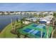 An aerial view showcasing a pickleball court, pool, lake, and houses in a beautifully landscaped community at 18044 Cherished Loop, Bradenton, FL 34211