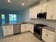 A modern kitchen with white cabinets, stainless steel appliances, and granite countertops overlooking the living room at 18044 Cherished Loop, Bradenton, FL 34211