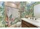 Well-lit bathroom with a decorative shower curtain and tropical wallpaper at 19921 Petrino St, Venice, FL 34293