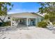 Charming blue beach house with white trim, a covered parking area, and lush tropical landscaping at 214 Palm Ave, Anna Maria, FL 34216