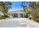 Charming blue beach house with white trim, a covered parking area, and lush tropical landscaping at 214 Palm Ave, Anna Maria, FL 34216