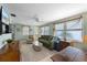 Bright living room with green sofa, large windows, ceiling fan, and coastal decorations at 214 Palm Ave, Anna Maria, FL 34216
