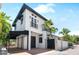 Stunning modern two-story home featuring a white exterior, black trim, and lush tropical landscaping at 324 Siesta Dr, Sarasota, FL 34242