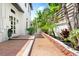A lush walkway with brick pavers leads to the entrance of this pristine white home at 324 Siesta Dr, Sarasota, FL 34242