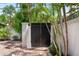 Elegant black gate surrounded by lush greenery and mature palm trees, offering privacy and security at 324 Siesta Dr, Sarasota, FL 34242