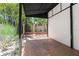 View of a brick-paved parking area with a metal awning and an ornate metal gate leading to tropical landscaping at 324 Siesta Dr, Sarasota, FL 34242