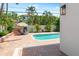 Inviting pool area with brick pavers, lounge chairs under a tiki umbrella, and lush tropical landscaping at 324 Siesta Dr, Sarasota, FL 34242
