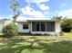 Exterior view of a house with a sunroom addition, surrounded by a lush green lawn at 3321 Fuller St # 105, Sarasota, FL 34231