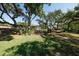 A single story home with a glass exterior, surrounded by large trees and a large lawn at 3402 Key Ave, Sarasota, FL 34239