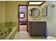 Bathroom featuring a large soaking tub, marble countertop sink, and doorway looking into the bedroom at 3406 67Th Street E Ct, Bradenton, FL 34208