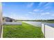 Well-maintained backyard featuring a serene lake view, lush green grass, and a white fence for privacy at 3478 74Th Avenue E Cir, Sarasota, FL 34243