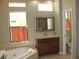 Bright bathroom featuring a soaking tub next to a window and a vanity with wood cabinets at 406 Petrel Trl, Bradenton, FL 34212