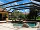 Gorgeous screened-in pool area with rock waterfall, spa, and built-in outdoor grill, perfect for entertaining at 406 Petrel Trl, Bradenton, FL 34212
