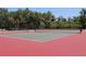 Two fenced tennis courts feature red and green playing surfaces surrounded by lush landscaping at 406 Petrel Trl, Bradenton, FL 34212