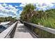 Elevated wooden boardwalk lined with lush vegetation, leading to the beach area and amenities at 452 Picasso Dr, Nokomis, FL 34275