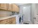 Well-equipped laundry room with side-by-side washer and dryer, storage cabinets, and bright neutral walls at 452 Picasso Dr, Nokomis, FL 34275