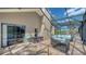 Screened-in patio with tiled floor, wicker furniture, and sliding glass door to the house, leading to the pool at 452 Picasso Dr, Nokomis, FL 34275