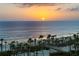 Beachfront view showcasing a sunset over the ocean with palm trees, white sand, and clear blue water at 535 Sanctuary Dr # A602, Longboat Key, FL 34228
