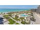 Luxury beachfront condo amenities featuring a pool, lounge area, beach access, and verdant landscaping on a sunny day at 535 Sanctuary Dr # A602, Longboat Key, FL 34228