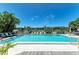 Community pool surrounded by lush landscaping and lounge chairs with a lake in the background at 5395 Lake Arrowhead Trl # 24, Sarasota, FL 34231
