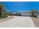 Well-maintained one-story home featuring a white roof, attached garage, and lush tropical landscaping at 606 Emerald Ln, Holmes Beach, FL 34217