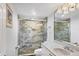Modern bathroom featuring a glass shower with stone tiling and a sleek vanity with decorative lighting at 625 Beach Rd # 207, Sarasota, FL 34242