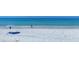 Serene beach scene with clear turquoise water, soft white sand, and a lone beachgoer under an umbrella at 625 Beach Rd # 207, Sarasota, FL 34242