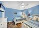 Bright bedroom featuring two twin beds with striped bedding, ceiling fan, and wood-look flooring at 625 Beach Rd # 207, Sarasota, FL 34242