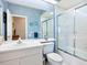 Clean bathroom featuring blue wallpaper, a large mirror, white sink, and a tiled shower with a glass door at 6748 Hickory Hammock Cir, Bradenton, FL 34202