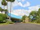 View of the community clubhouse with a blue roof, palm trees, and golf carts parked nearby at 6748 Hickory Hammock Cir, Bradenton, FL 34202